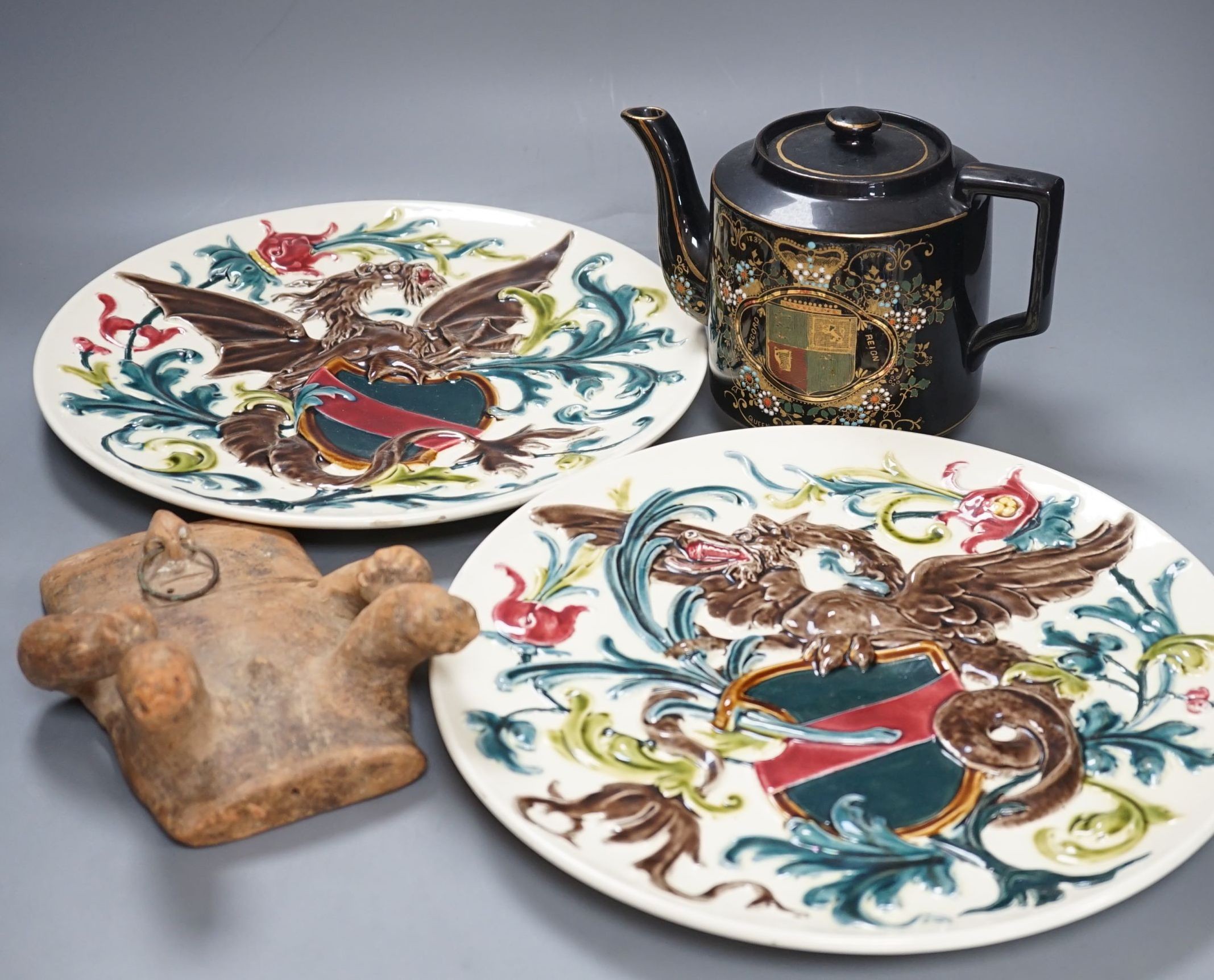 A pair of French pottery dragon & shield dishes, a Queen Victoria Diamond Jubilee teapot and a Quimbaya Culture clay figure, dishes 32 cms diameter.